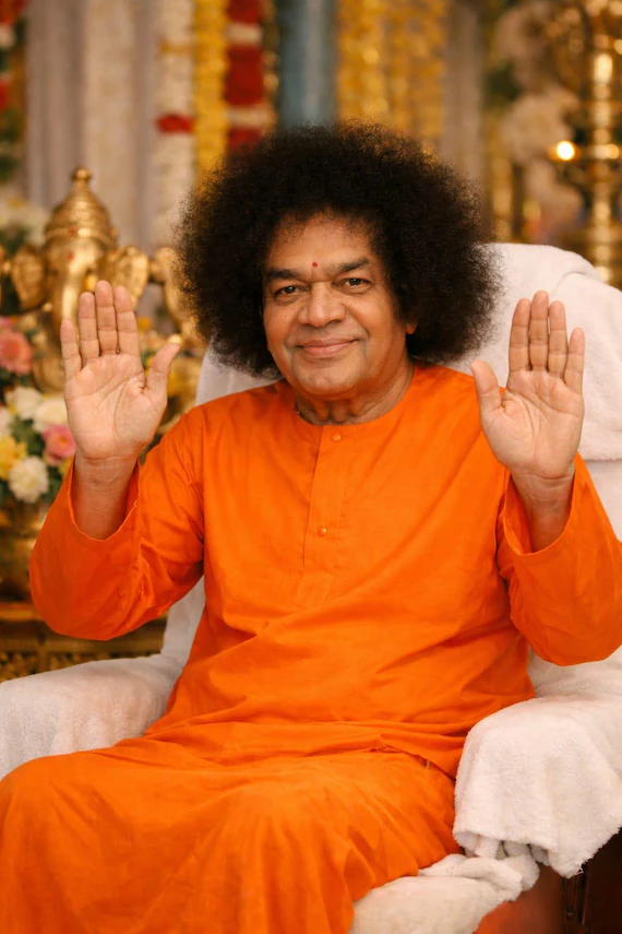 Bhagawan Sri Sathya Sai Baba in orange robes, blessing with both hands raised